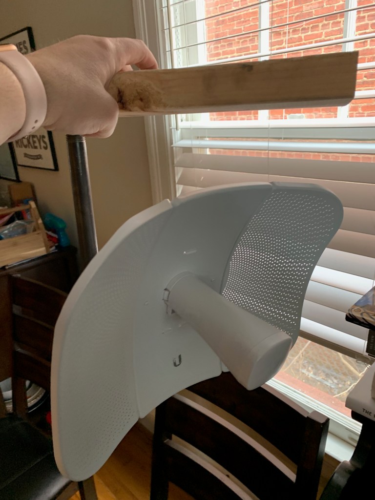 A LiteBeam dish hanging from a pipe mount beneath a 2x4