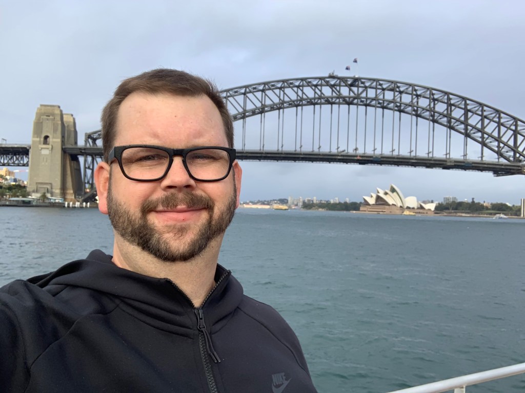 Tom Bridge standing in front of Harbour Bridge and Sydney Opera House
